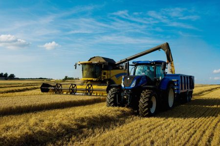 Combine harvester and tractor harvesting a crop in a field in summer.