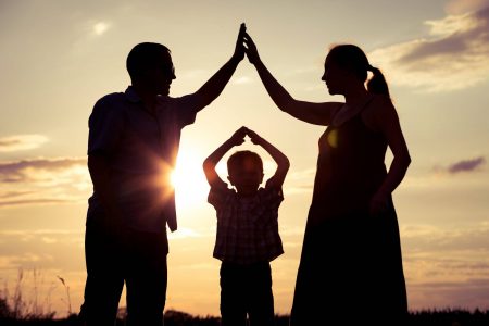 Happy family standing in the park at the sunset time. People having fun outdoors. Concept of friendly family.